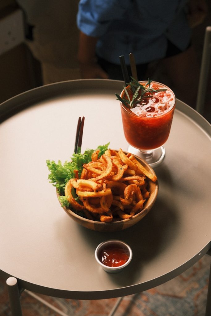 Curly fries with ketchup and a strawberry drink
